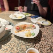 a woman sitting at a table with plates of sushi
