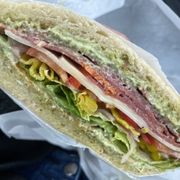 Salami, provolone, spicy capicolla, pesto spread, red bells, pepperoncini, lettuce, tomatoes, onions, and house made pickles