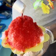 a person pouring ketchup on a sandwich
