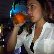 a woman drinking a beer at a bar