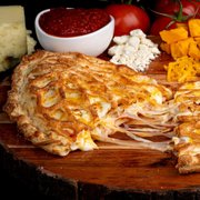 a wooden cutting board with cheese, meat, and vegetables