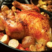 a roast chicken in a skillet with potatoes