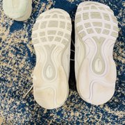 The two shoes side by side. One dirtier and yellow other less dirty and very crisp white.