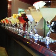 a row of cocktails lined up on a bar