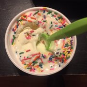 a cup of yogurt with sprinkles and a spoon