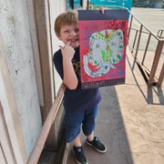 a young boy holding up a painting