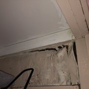 a corner of a room with a hole in the ceiling