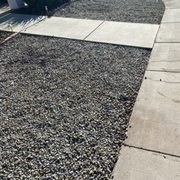 Brown grout water dumped into rocks, leaving stain and stained sidewalk