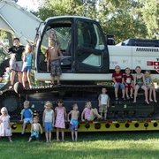 a group of children standing on the back of a large excavator