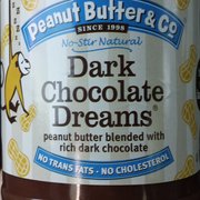 a hand holding a jar of peanut butter and co