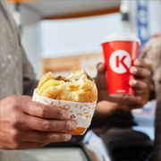 a person holding a sandwich and a drink