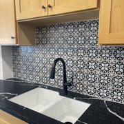 Honey shaker on maple with a horizon black quartz and a Cloe Casablanca rialto tile backsplash.