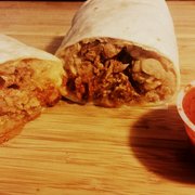 Pastor burrito cross section with red salsa.