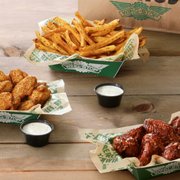 three baskets of chicken wings and two dipping sauces