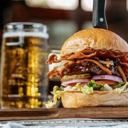 a burger with bacon, lettuce, tomato, and onion