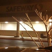 a parking lot at night with a tree in the foreground