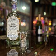 a bottle and a shot glass on a bar