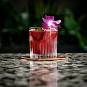 a pink cocktail with a purple flower