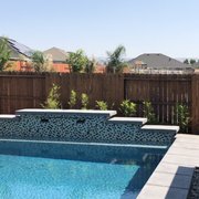 Three tiered custom raised wall with glass tile, sheer descent water fall and lighting.