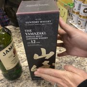 a hand holding a bottle of suntory whisky
