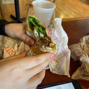 a person eating a pita sandwich