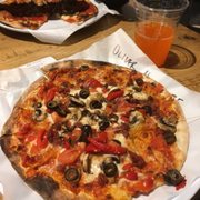 Pizza with tomatoes, red peppers, mushrooms, black olives, and bacon