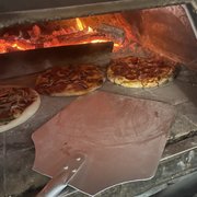  a pizza being cooked in a brick oven