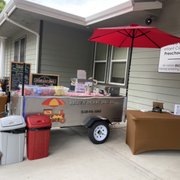 a hot dog cart with a red umbrella