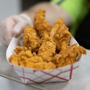 a person holding a basket of fried chicken