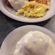 Chicken fried steak with a biscuit and gravy.
